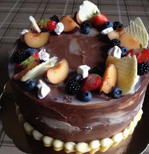 Chokladtårta täckt med ganache, plommon, björnbär och färska bär
