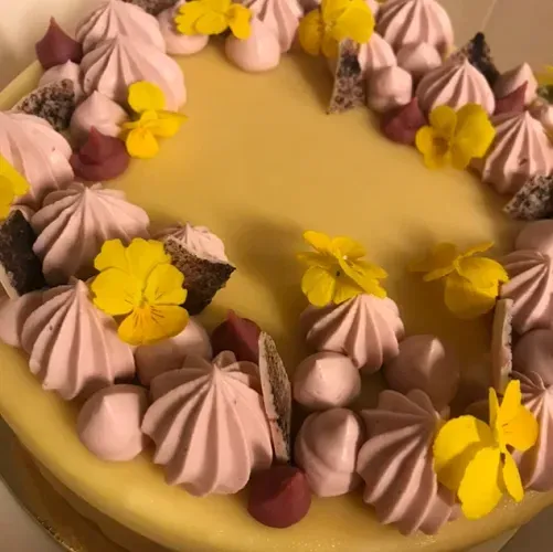 Tårta med passionsfruktsglasyr, rosa maränger och gula violer